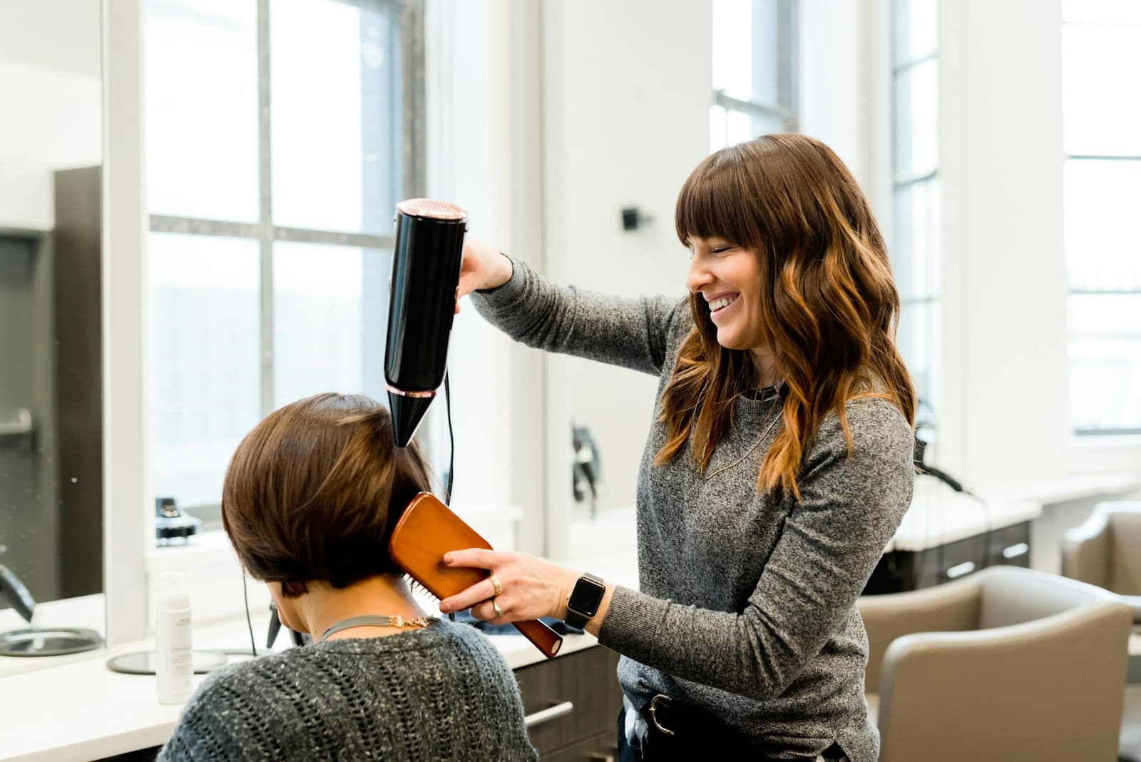 Coafeză uscând părul unei cliente în salon